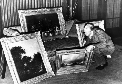 Een Engelse officier bekijkt kunstschatten in het huis van een hoge Nazi-officer te Hannover, waaronder ook Nederlandse werken